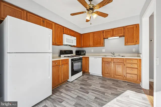 a kitchen with a refrigerator a stove a sink dishwasher and a dining table with wooden floor