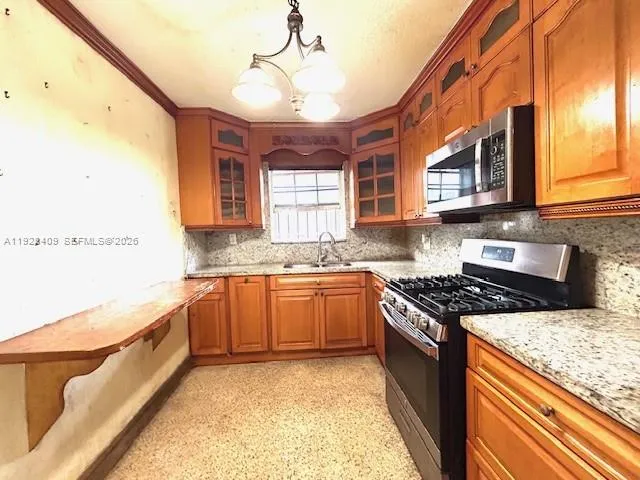 a kitchen with stainless steel appliances granite countertop wooden cabinets a stove a sink and a microwave