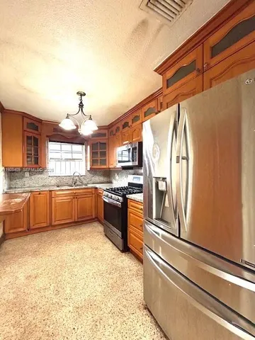 a large kitchen with stainless steel appliances granite countertop a sink and a refrigerator