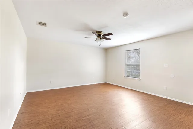 an empty room with a window and a ceiling fan