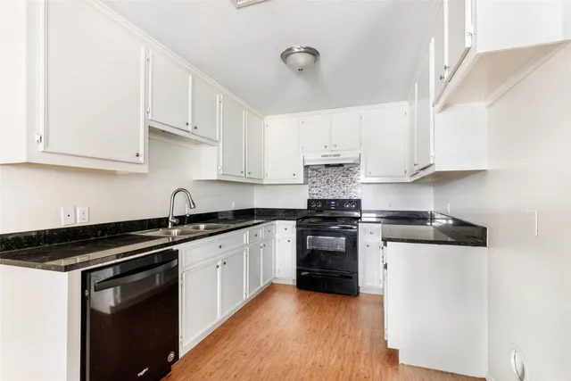 a kitchen with stainless steel appliances granite countertop a stove and white cabinets