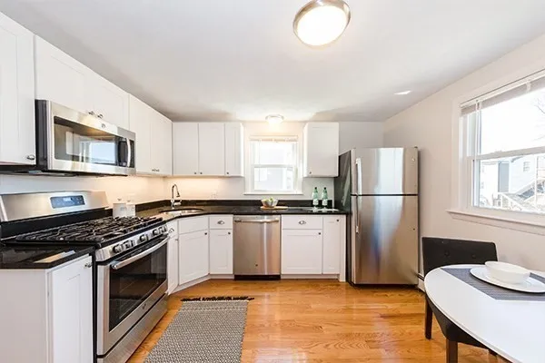 a kitchen with a refrigerator a stove a sink cabinets and a window