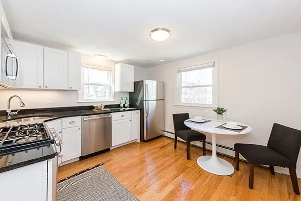a kitchen with stainless steel appliances a table and chairs in it