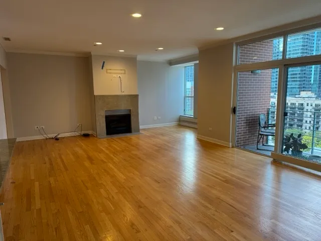 an empty room with wooden floor fireplace and windows