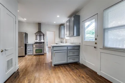 a kitchen with stainless steel appliances a sink window and wooden floor