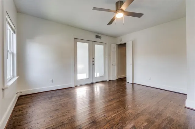 a view of empty room with wooden floor and fan