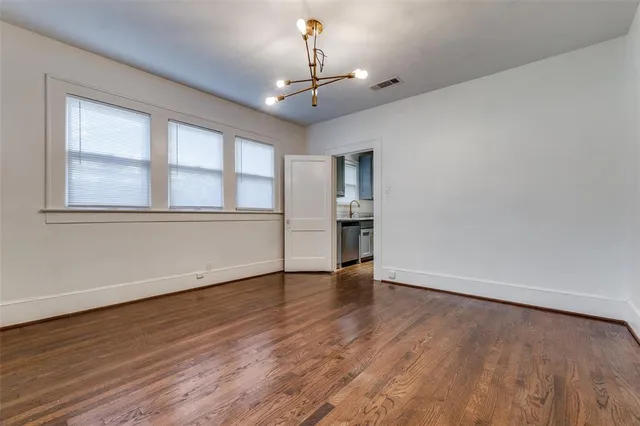 a view of an empty room with wooden floor fireplace and a window