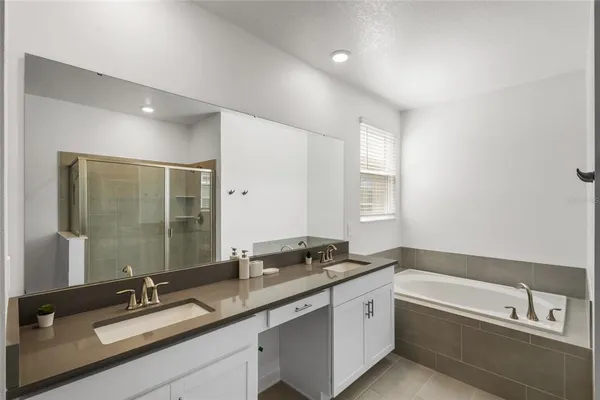 a bathroom with a sink double vanity granite tub and a mirror