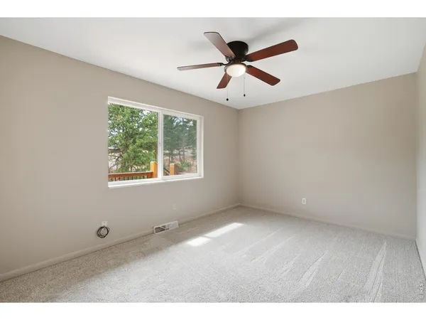 a view of an empty room with wooden floor and window