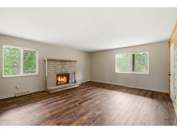 an empty room with windows and fireplace