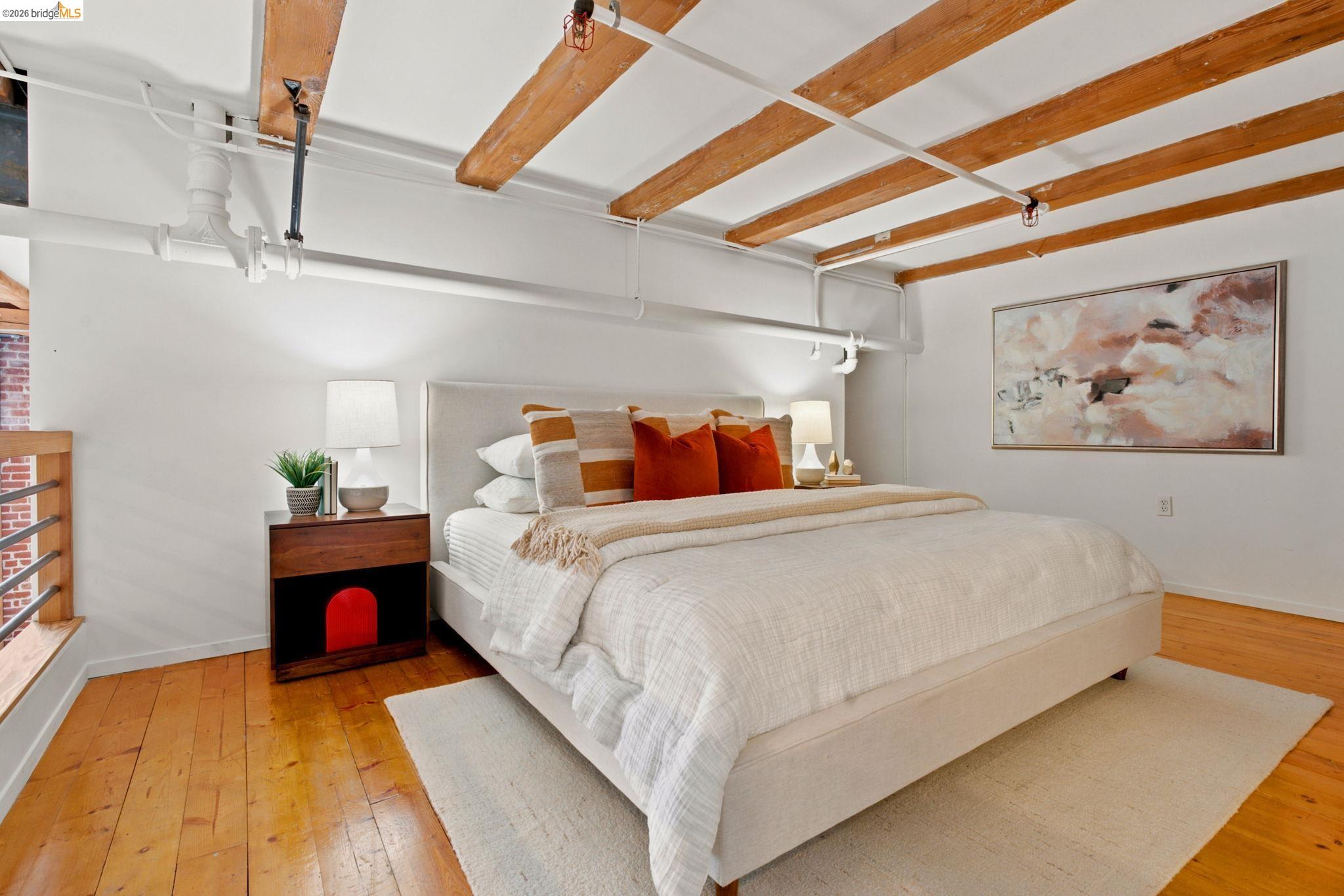 1920 Union Street, Unit 9 Oakland, CA 94607 - Photo 20 of 35 Room featuring exposed wood ceiling beams, wood-finish flooring, white walls, and industrial-style exposed piping