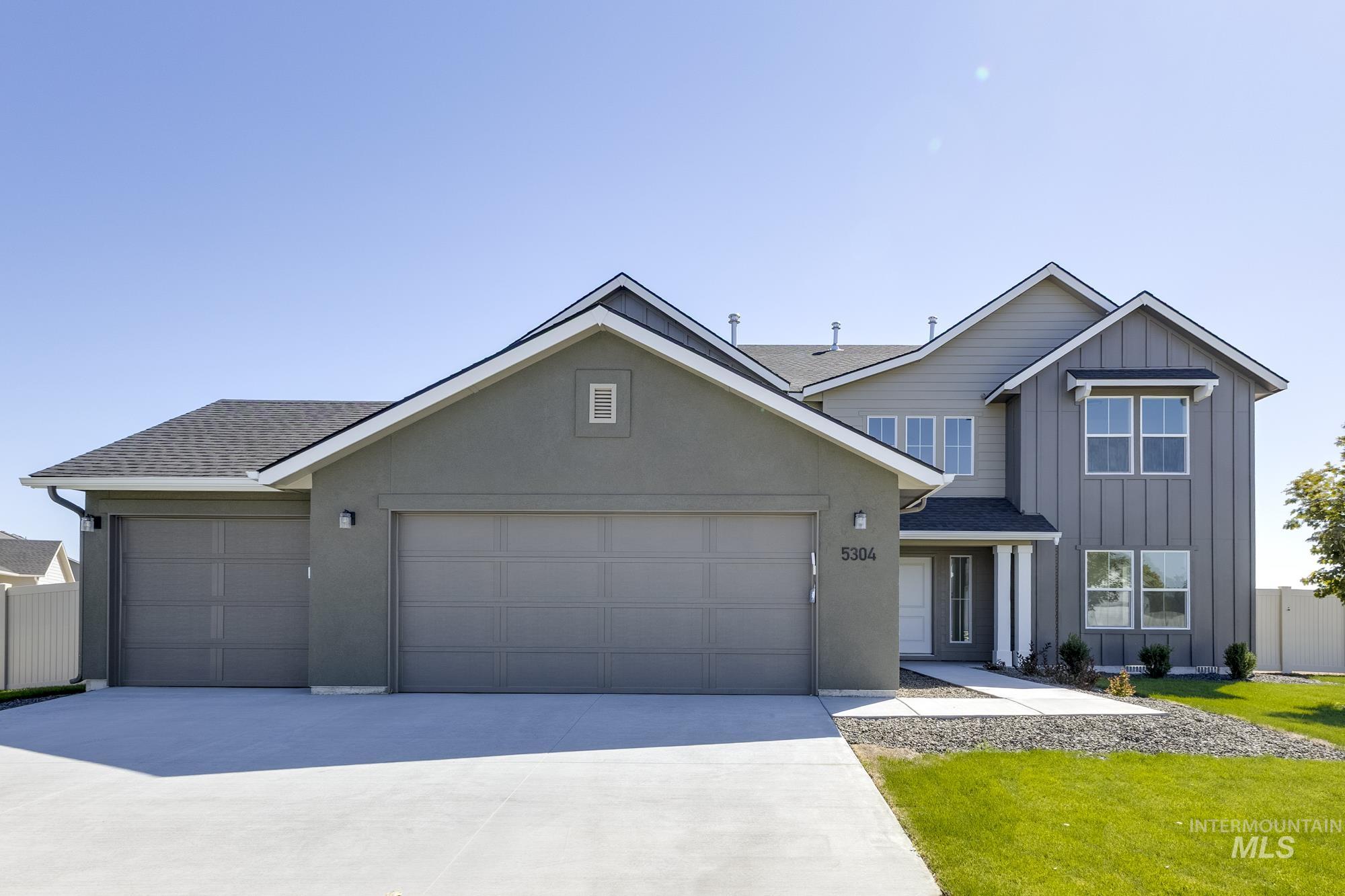 View of front facade featuring a shingled roof, board and batten siding, an attached garage, and driveway