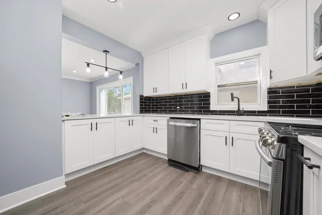 a kitchen with granite countertop a stove a sink and white cabinets with wooden floor