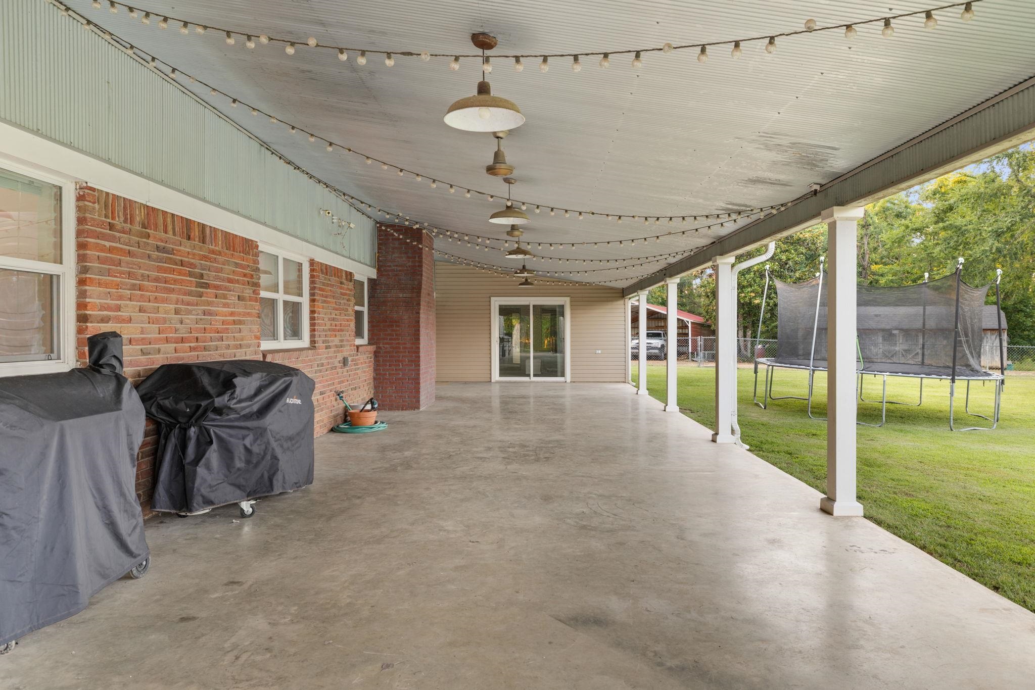 66 County Road 511 Corinth, MS 38834 - Photo 30 of 40 Expansive covered patio with concrete flooring, brick exterior wall, and white support columns