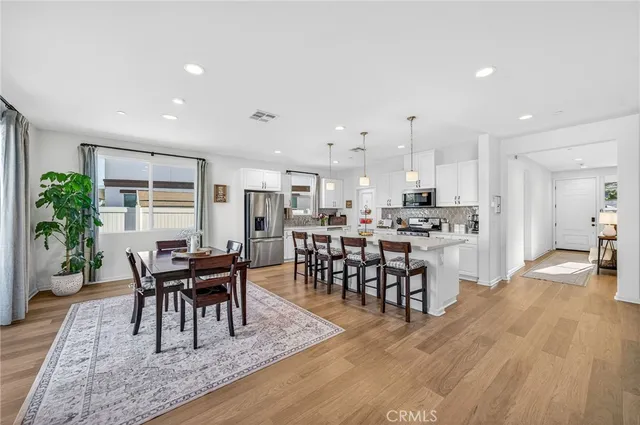 a kitchen with stainless steel appliances kitchen island granite countertop a table chairs sink and cabinets