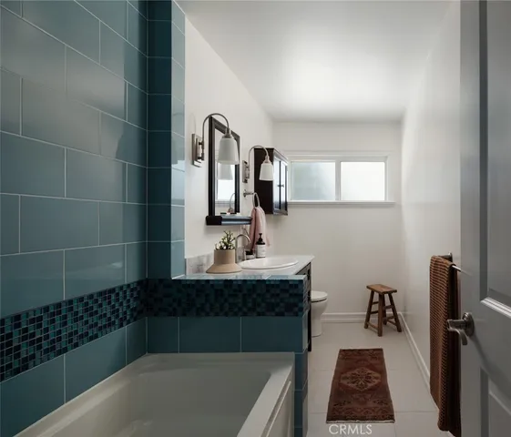 a bathroom with a bathtub sink vanity and mirror