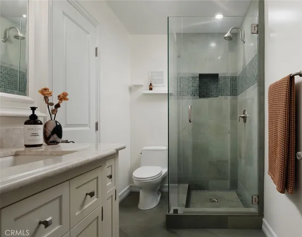 a bathroom with a granite countertop sink a toilet and shower