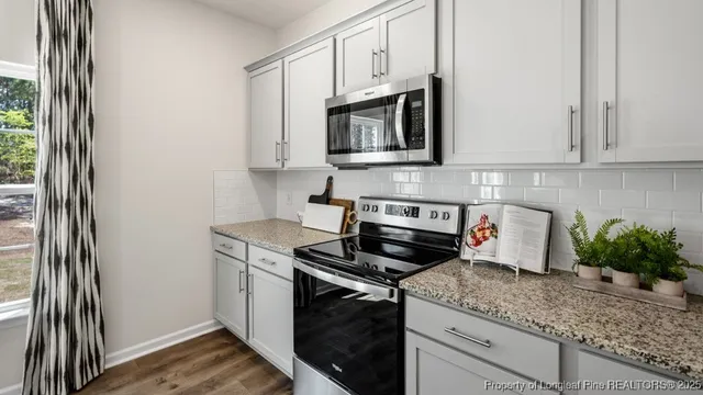 a kitchen with stainless steel appliances granite countertop white cabinets and a stove