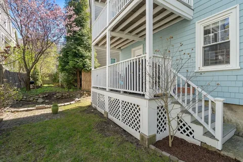 a view of a brick house with backyard and wooden fence