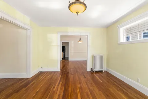 a view of empty room with window and wooden floor