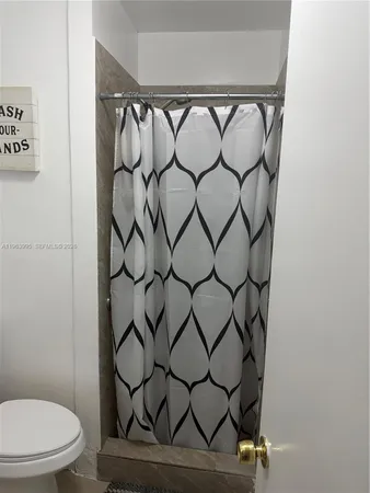 a bathroom with a toilet and a shower curtain