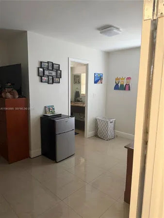 a living room with furniture and a refrigerator