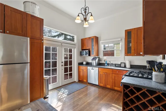 a kitchen with stainless steel appliances granite countertop a refrigerator a sink dishwasher a stove with wooden cabinets and floor