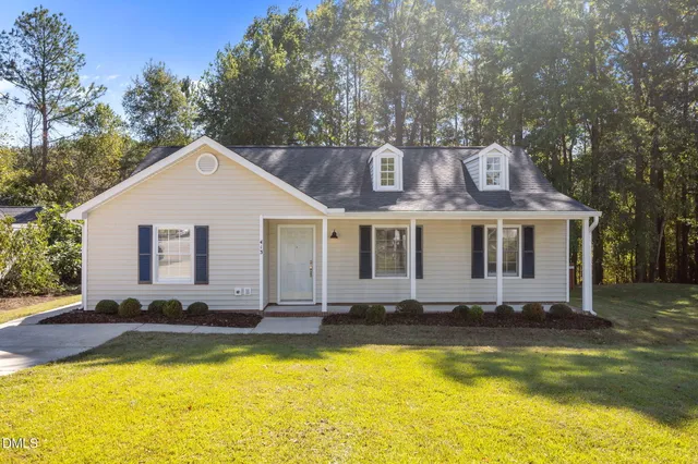 a front view of house with swimming pool and trees in the background