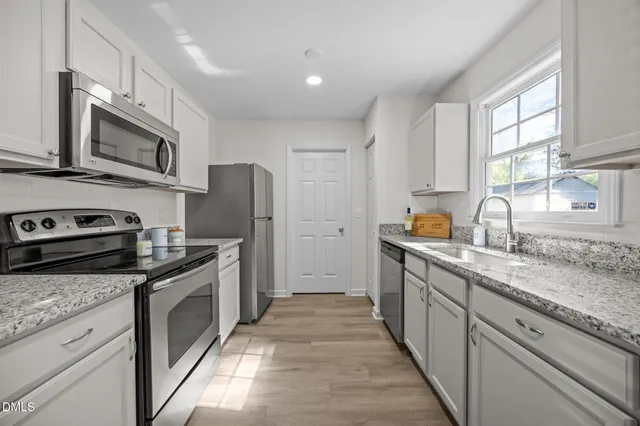 a kitchen with stainless steel appliances granite countertop a stove top oven a sink dishwasher a refrigerator and cabinets with wooden floor