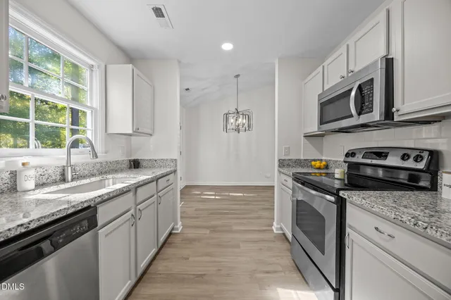 a kitchen with stainless steel appliances granite countertop a sink and a stove