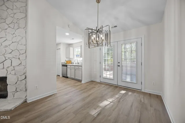 a view of an empty room with wooden floor and kitchen view