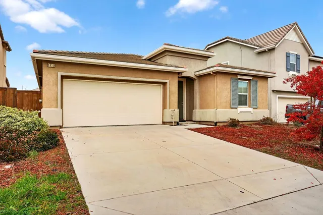 a view of a white house with a small yard and potted plants