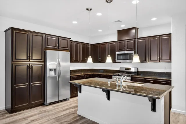 a kitchen with stainless steel appliances granite countertop a stove a refrigerator and a microwave