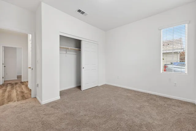 a view of an empty room with closet and a window