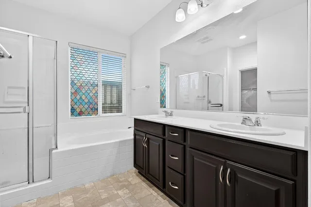 a bathroom with a tub double sink window and mirror