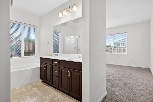 a spacious bathroom with a tub double sink and mirror