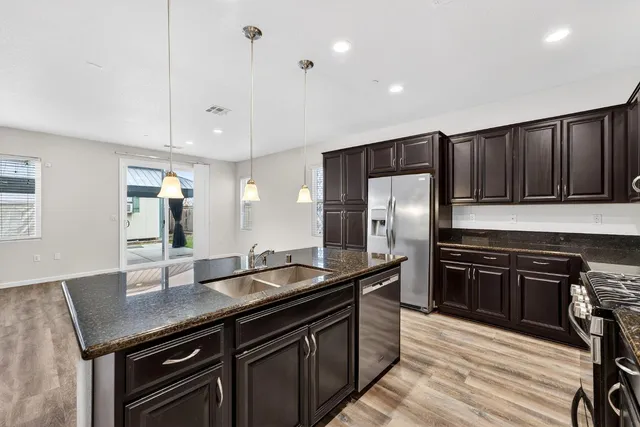 a kitchen with stainless steel appliances granite countertop a sink stove and refrigerator