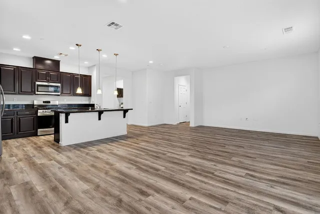 a view of kitchen with stainless steel appliances granite countertop a stove top oven a sink and a microwave