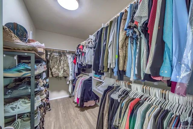 a view of walk in closet with clothes and shoes