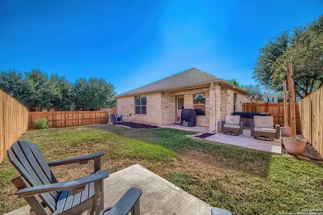 a view of a backyard with table and chairs couches and wooden fence