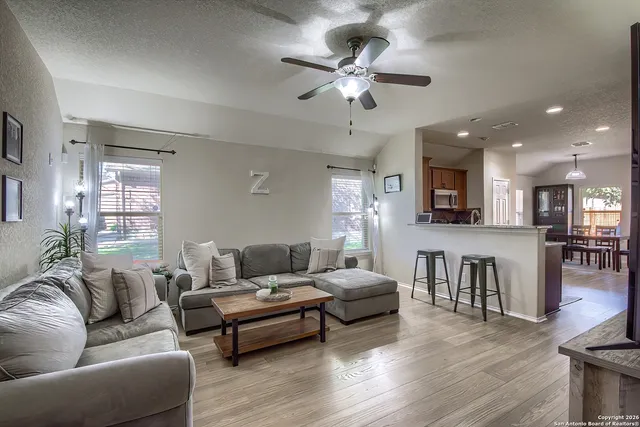 a living room with furniture kitchen view and a wooden floor