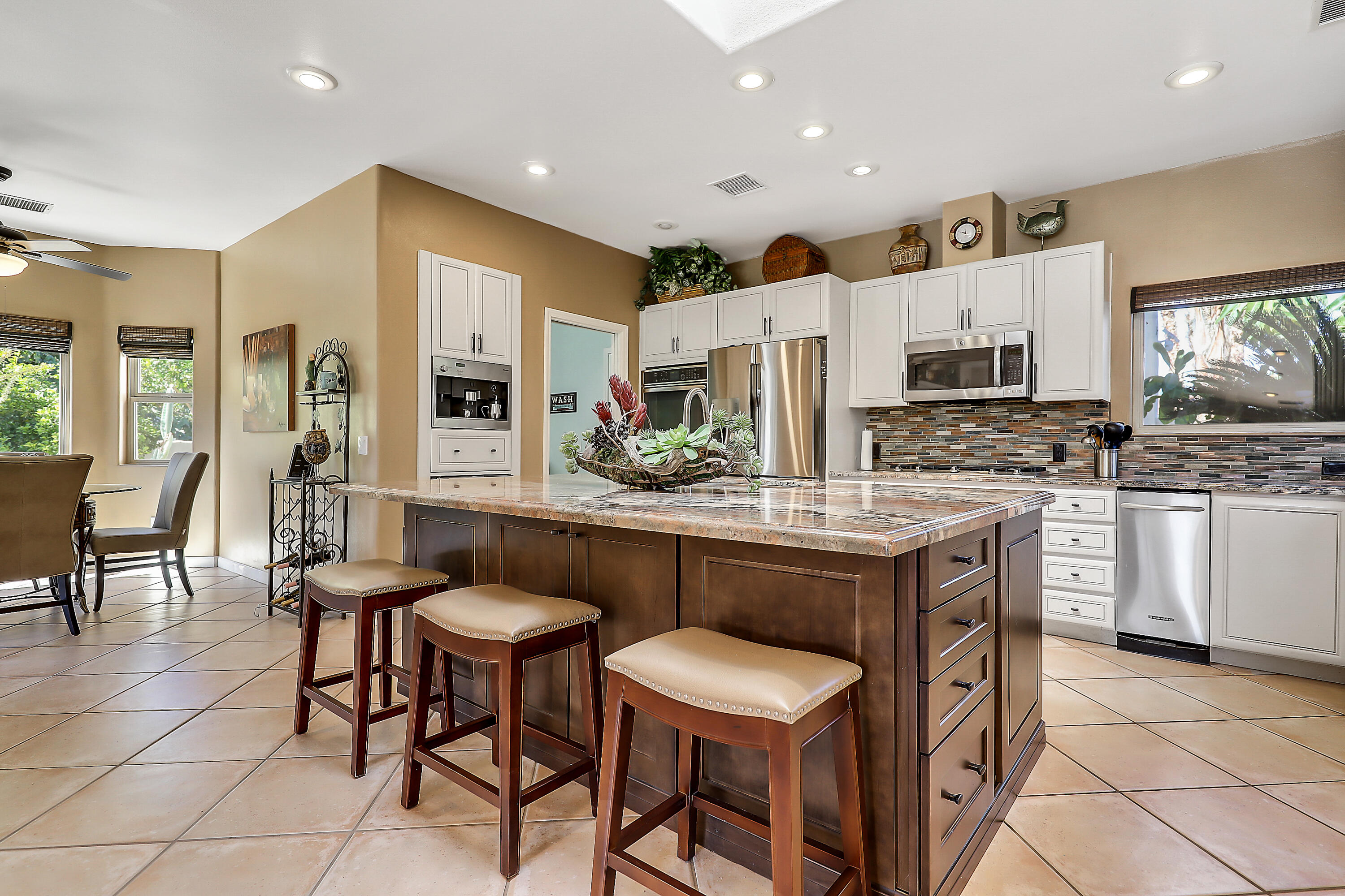 72447 Magnesia Falls Drive Rancho Mirage, CA 92270 - Photo 16 of 50 a kitchen with stainless steel appliances a table chairs and a refrigerator