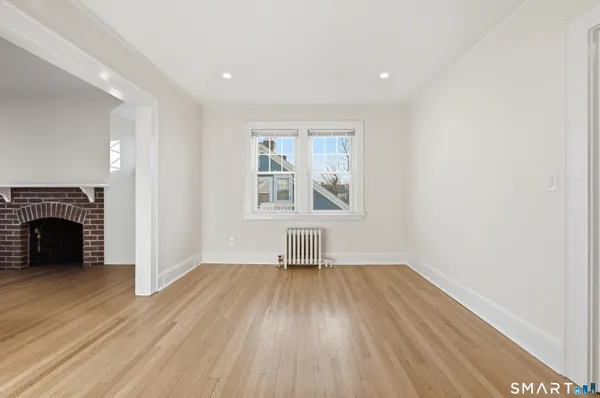 an empty room with wooden floor a fireplace and windows