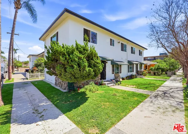 a front view of a house with a yard and potted plants