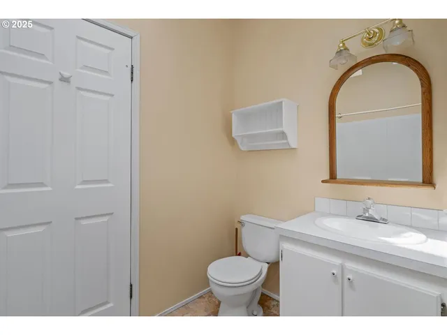 a bathroom with a toilet sink vanity and mirror