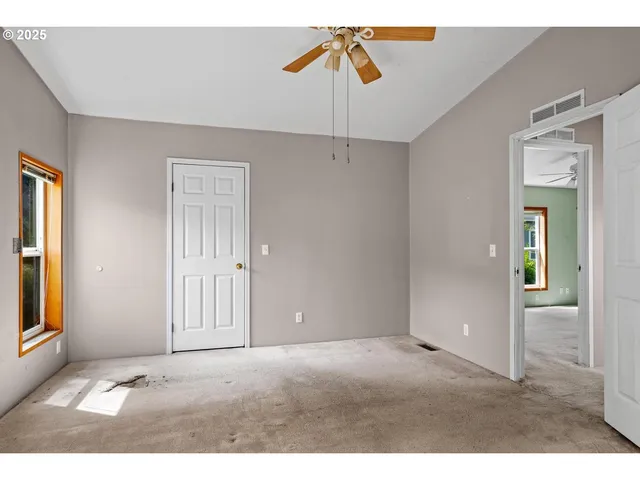 a view of an empty room with closet and a window