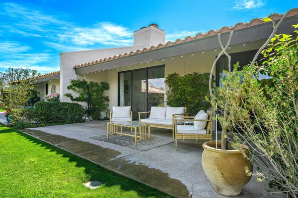 a view of a patio with couches table and chairs and potted plants