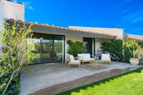 a view of a patio with table and chairs potted plants and floor to ceiling window