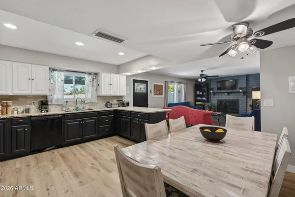 a large kitchen with stainless steel appliances kitchen island granite countertop a table chairs in it and wooden floors
