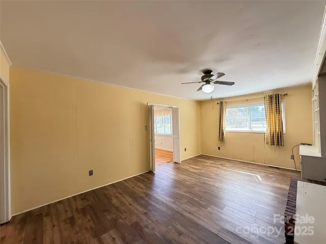 a view of an empty room with wooden floor and a window